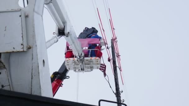 Trabajador en reparaciones uniformes líneas eléctricas en cesta de grúa de camión — Vídeo de stock