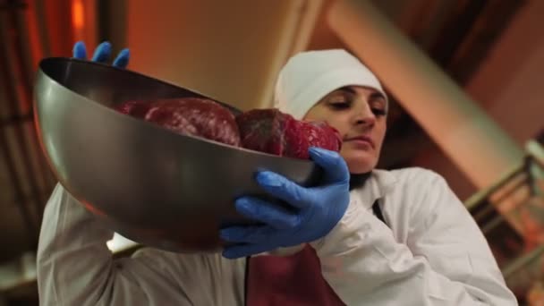 Mujer vierte trozos de carne de res de cuenco de metal en taller — Vídeos de Stock