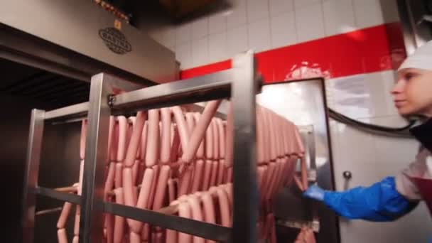 Женщина кладет вешалку со свежими сосисками в духовку в магазине — стоковое видео