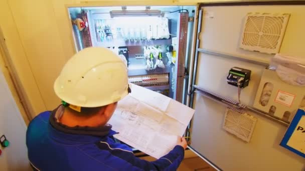 Technician looks at drawing near switchboard at substation — Stock Video