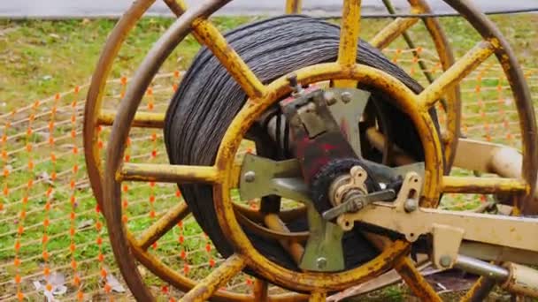 Old yellow bobbin with wire and turning chain on green grass — Stock Video