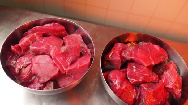 Великі миски з нарізаним яловичим м'ясом на столі в рослинній майстерні — стокове відео