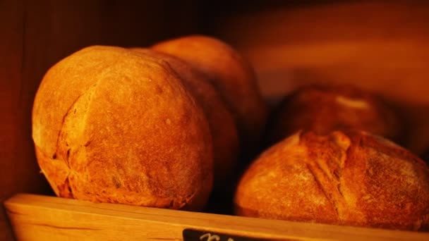 Fresh bread loaves on wooden shelf at modern bakery shop — Stock Video