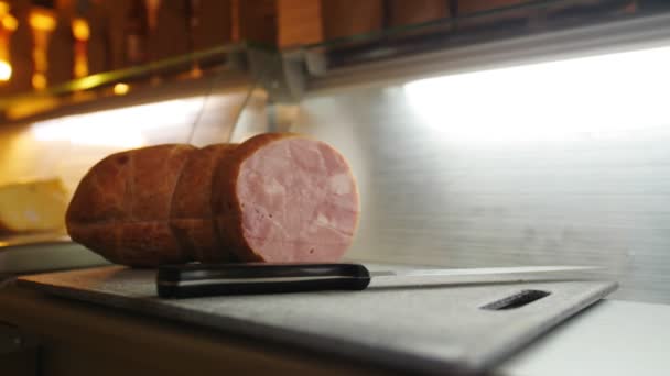 Cortar salchichas y cuchillo en la encimera por escaparate en la tienda de comestibles — Vídeo de stock