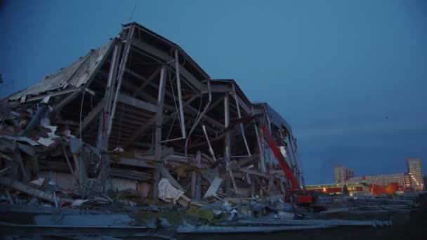 Excavadora cerca de la arena de hockey destruido en la noche de primavera — Vídeo de stock