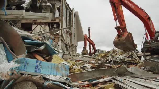 Excavatrices démanteler les décombres près du stade sous un ciel nuageux — Video