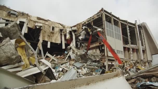 Excavadora roja desmantela escombros de estadio de hockey abandonado — Vídeos de Stock