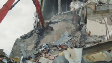Kazı makinesi eski beton duvarları kesiyor.
