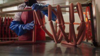 İşçi dükkandaki raflara lezzetli çiğ sosisler koyar.