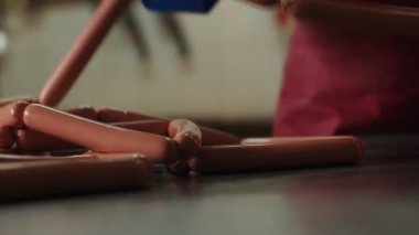 İşçi atölyedeki metal masasında taze çiğ sosisleri kontrol ediyor.