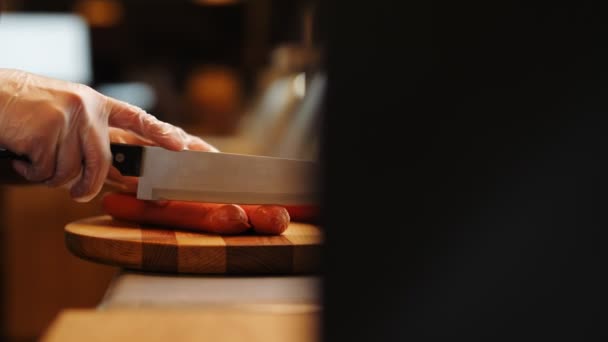 Vendedora corta deliciosas salchichas a bordo en el mostrador — Vídeos de Stock