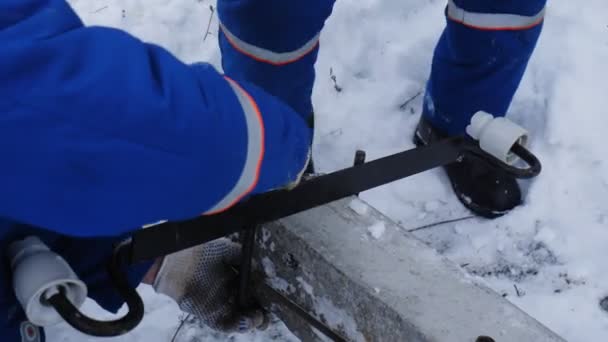 労働者は雪の地面に装置を設置するネジを — ストック動画