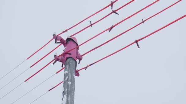 Polo superior y cables con material rosa contra el cielo gris — Vídeo de stock