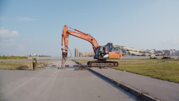 Excavadora camión hace pozo en la carretera cerca del estadio en el día de primavera — Vídeo de stock