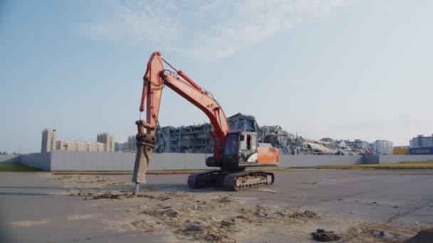 Máquina cava pozos bajo control obrero cerca del sitio de demolición — Vídeo de stock