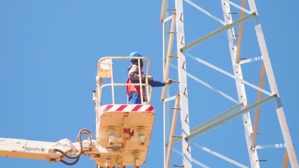 Arbeiter mit Helm kontrolliert Strommast aus Korb — Stockvideo