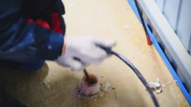 Elektrikçi istasyonun zemininde kabloyu deliğe sokuyor.