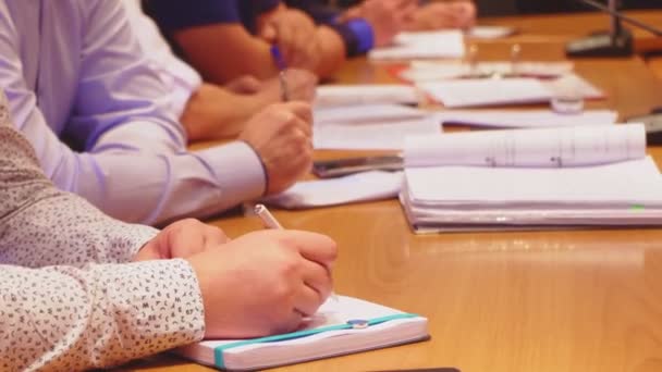 Empresários com blocos de notas sentam-se à mesa na reunião diária — Vídeo de Stock