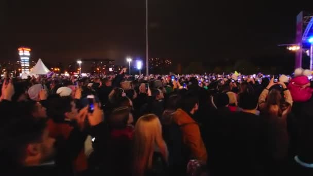 Music fans with cellphones watch show in winter evening — Stock Video