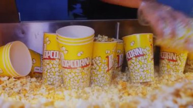 Kadınlar fast food kafede kağıt bardakları lezzetli patlamış mısırla doldurur.