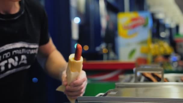 Férfi hozzá mustár ízletes friss hot-dog a gyorsétterem kávézó — Stock videók