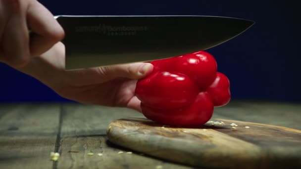 ボード上のおいしい熟した赤ピーマンの一部を切断する人 — ストック動画