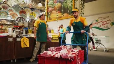 Üniformalı adam departmana çiğ etle kamyon taşıyor.