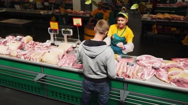 Vendedora serve comprador no departamento de carne de porco no mercado — Vídeo de Stock
