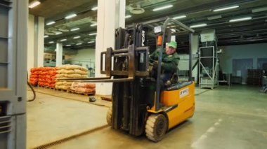 İşçi forklift yükleyicisini patatesli kutuyu almak için kullanıyor.