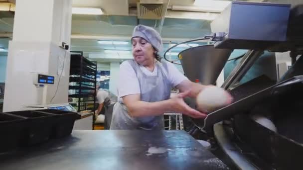 Женщина проверяет сырые булочки возле производственной линии в пекарне — стоковое видео