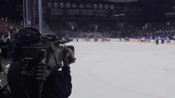 Operatör filmer hockey spel med kamera på modern isarena — Stockvideo