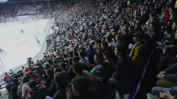 Movimento sobre os fãs assistindo jogo de equipes favoritas na pista de gelo — Vídeo de Stock