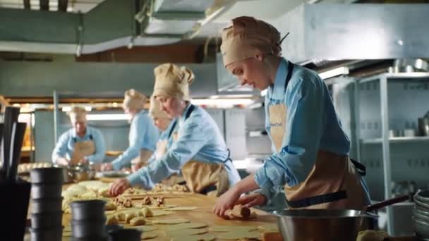 Mädchen rollt Teigstück backt Kuchen am großen Tisch in Bäckerei — Stockvideo