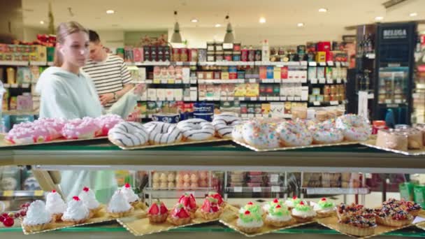 Lány bevásárlókosár választ finom sütemények a piacon — Stock videók