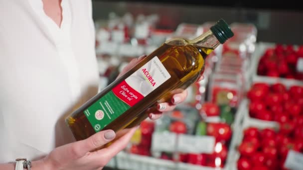 Женщина смотрит на оливковое масло делает покупки в супермаркете — стоковое видео