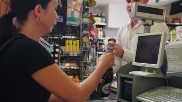 Человек дает шампанское и сыр кассиру в супермаркете — стоковое видео