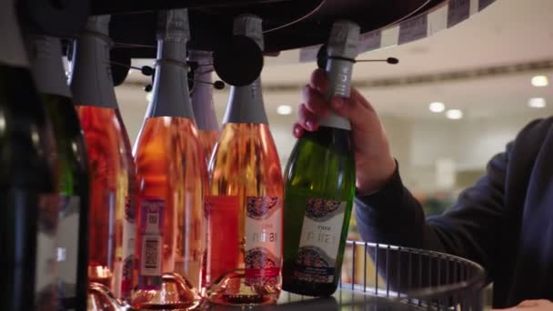 Человек выбирает вкусное шампанское в современном супермаркете — стоковое видео