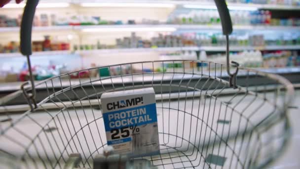 Pessoa joga coquetel de proteína em cesta no supermercado — Vídeo de Stock