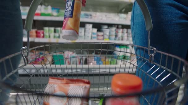 Женщина бросает йогурт в корзину для покупок в супермаркете — стоковое видео