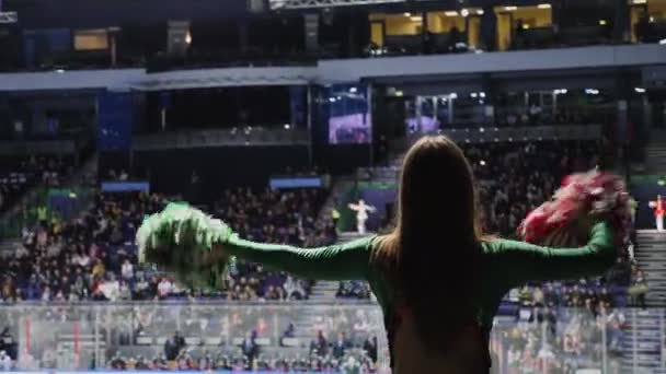 댄서가 하키 선수들을 응원하기 위해 밝은 포 피스를 흔들고 있습니다 — 비디오