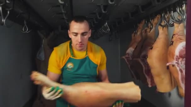 Operaio in grembiule mette grandi pezzi di carcasse di maiale sul carrello — Video Stock
