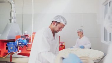 Çalışanlar fırında makineli aletle taze ince pide yapıyorlar.