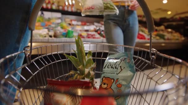 Señora en jeans pone paquete de ensalada verde en la cesta de amigos — Vídeos de Stock