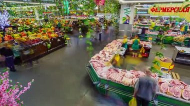 İnsanlar markette et ve meyve reyonlarıyla dolaşıyorlar.