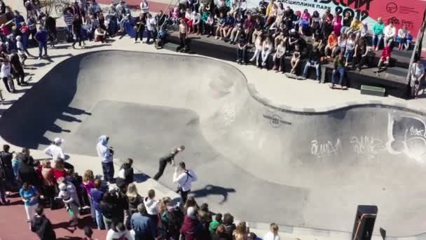 Skater rides board in large pool before spectators in park — Stock Video