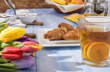 parlak laleler, limonlu çay, beyaz bir plaka üzerinde hamur işleri 