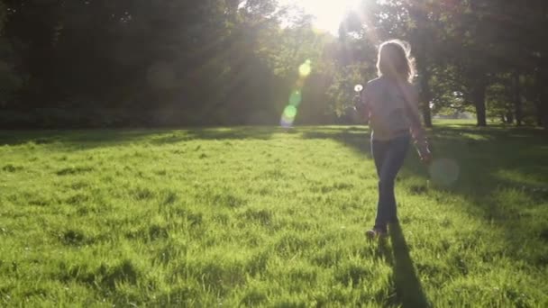 Vrolijk meisje in park scheurt paardebloemen — Stockvideo