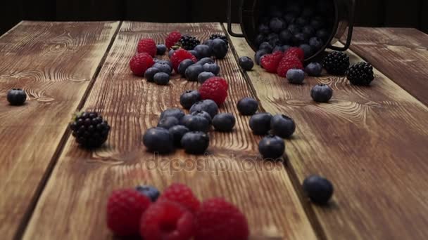 Egészséges, vegyes gyümölcs, áfonya. Friss bogyós gyümölcsök, szeder, málna, a fából készült asztal — Stock videók