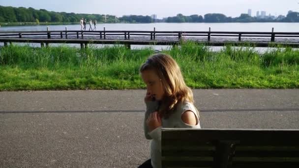 Menina falando no telefone com amigo, menina feliz no parque jogando no smartphone — Vídeo de Stock