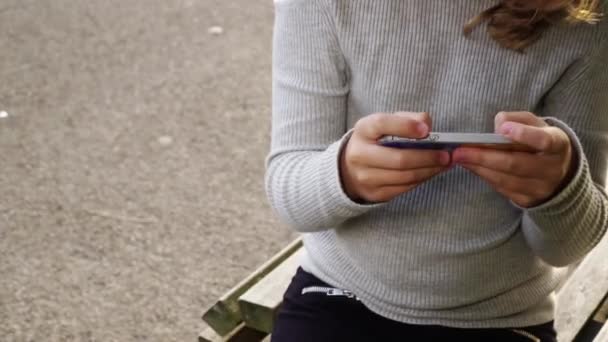 Chica hablando por teléfono con un amigo, Chica feliz en el parque jugando en el teléfono inteligente — Vídeos de Stock